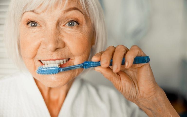Elderly woman burshing her teeth