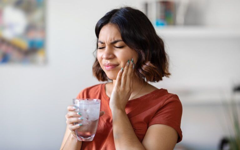 Woman experiencing sensitivity from drinking cold water
