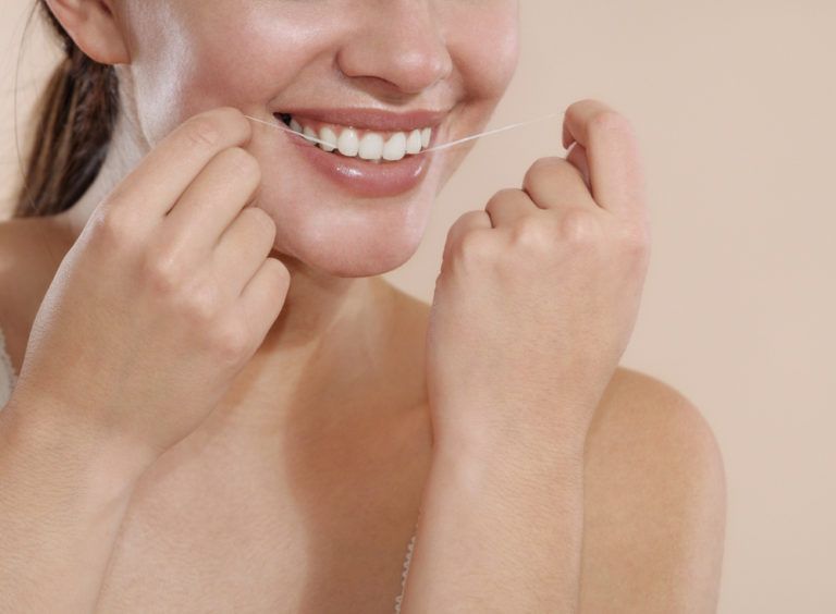 Beautiful woman cleaning teeth with dental floss