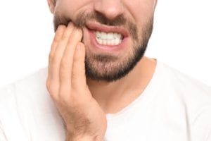Man with tooth pain holding his lower jaw