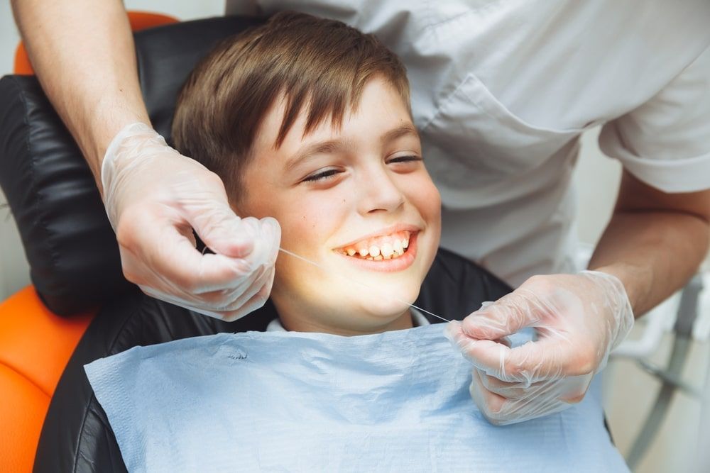 the dentist brushes the boy's teeth with dental floss. oral hygiene in children. pediatric dentistry. flossing your teeth.