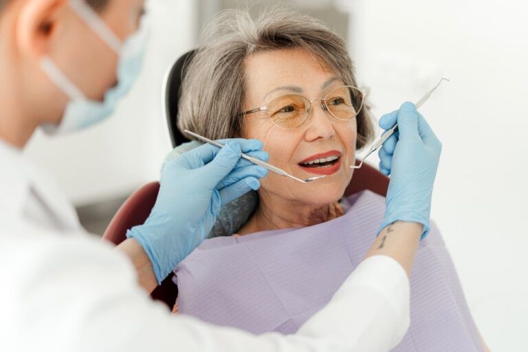 Attractive senior woman, patient sitting in dental chair with open mouth professional doctor holding dental tools, checking teeth