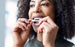 Woman Putting On Invisalign Clear Aligners