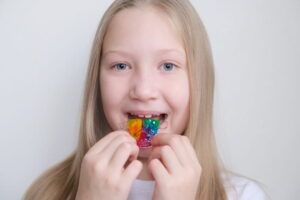 The child holds an orthodontic plate in his hands to align the teeth and expand the jaw.