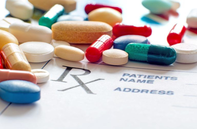 close up of a variety of prescription pills scattered over a prescription notepad