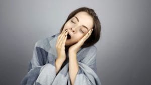 Drowsy woman wrapped in a blanket and yawning
