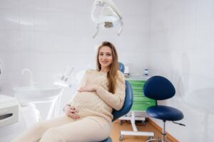 A professional dentist treats and examines the oral cavity of a pregnant girl in a modern dental office. Dentistry