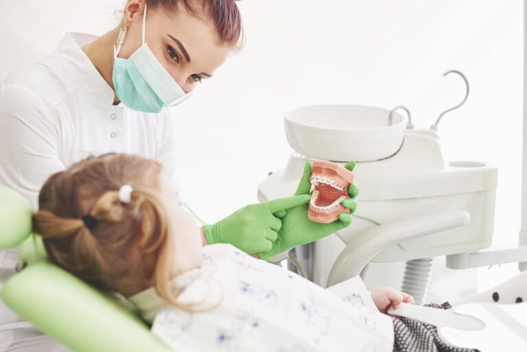 Little girl in dentists chair, being educated about proper tooth-brushing by her paediatric dentist.