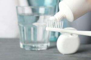 Toothbrush with toothpaste on background with dental care tools, close up