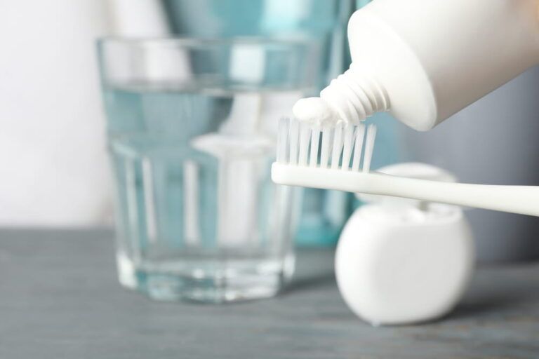 Toothbrush with toothpaste on background with dental care tools, close up