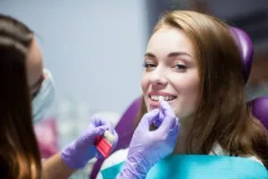 female patient in dental chair and female hygienist comparing tooth for a crown