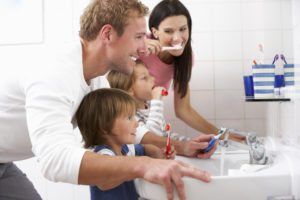 family with kids in the bathroom brushing their teeth