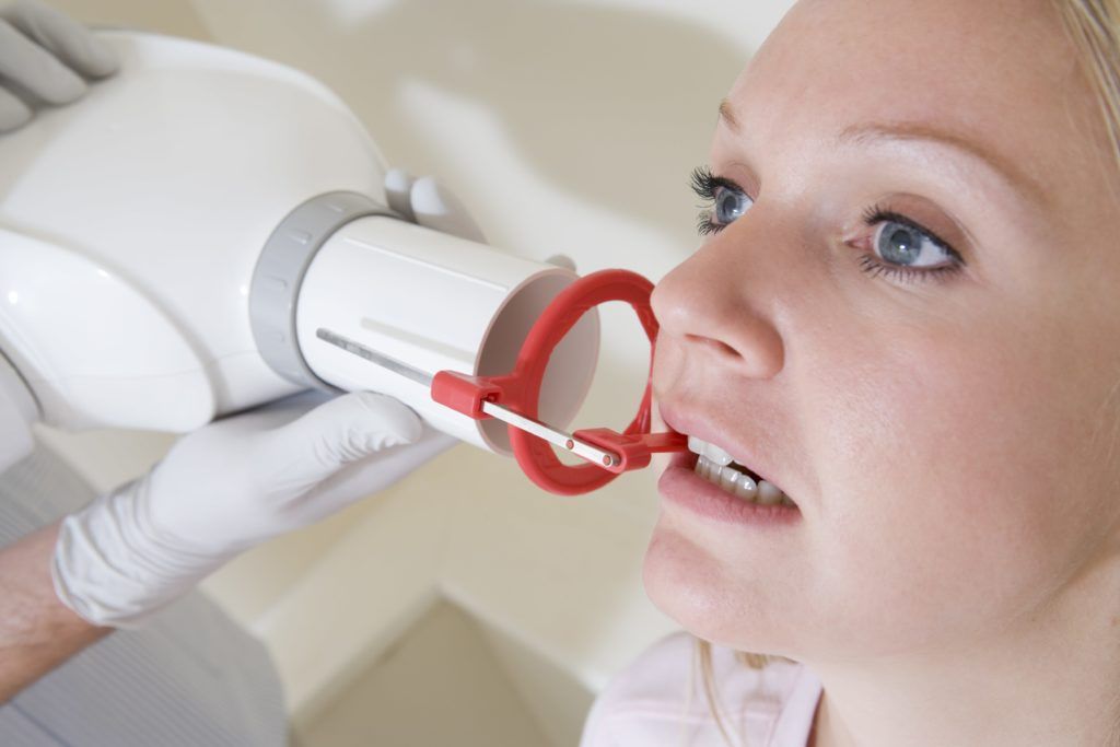 Woman biting down on a dental xray machine mouthpiece