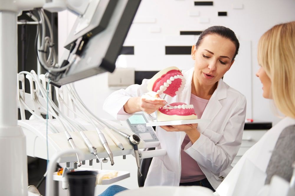 Dentist using a tooth model to explain something to patient