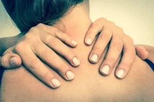 Woman reaching back and using her hands to massage her upper shoulders