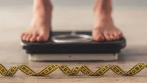 Person standing on scale with measuring tape