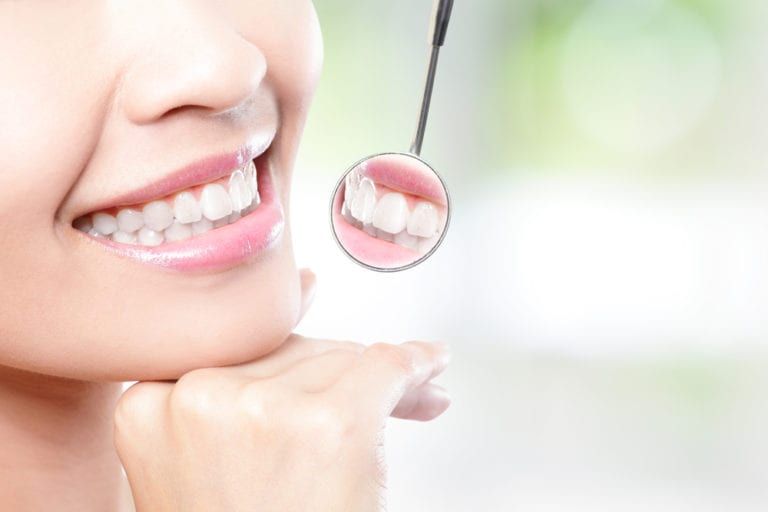 Healthy woman teeth and a dentist mouth mirror