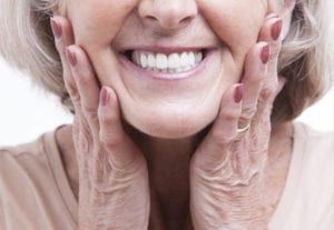 senior woman touching dentures