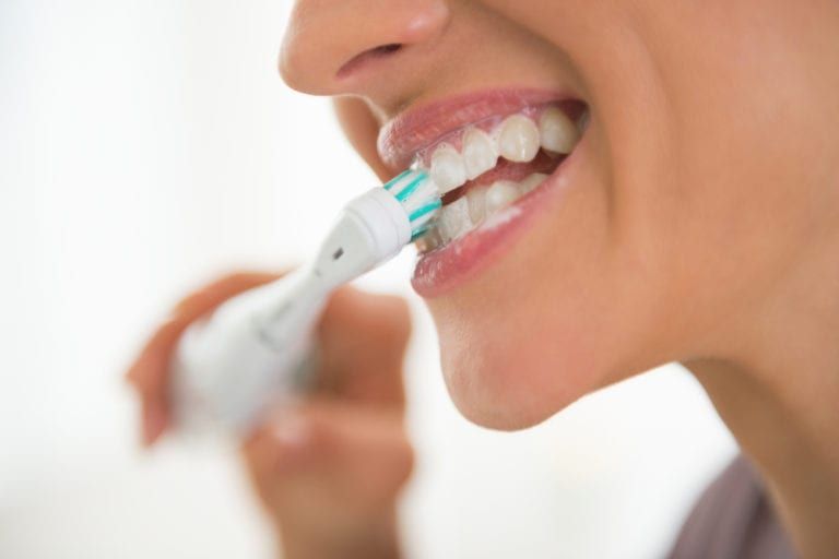 woman brushing teeth with Electric Brush