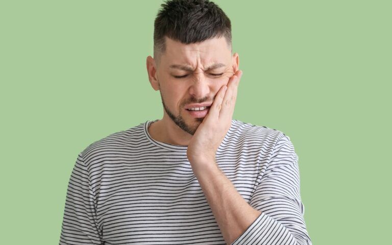 Man Experiecing Tooth Pain From Abscess With Green Background