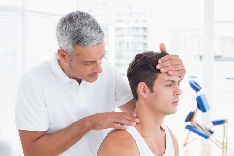 Chiropractor performing a physical exam on a patient that has back and neck pain due to chronic tight muscles and playing golf.